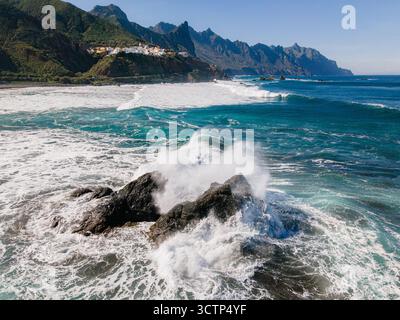 Foto aeree grandangolari che mostrano le onde che si infrangono drammaticamente contro le scure rocce vulcaniche lungo l'aspra costa settentrionale di Tenerife, Spagna. Foto Stock