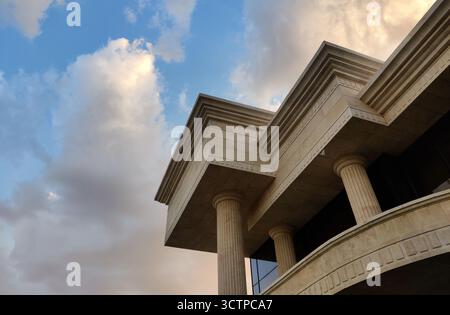 Una vista dall'angolo basso mette in risalto le maestose colonne e gli intricati dettagli di un edificio classico. La struttura è incorniciata da un cielo vibrante e da nuvole spettacolari. Foto Stock