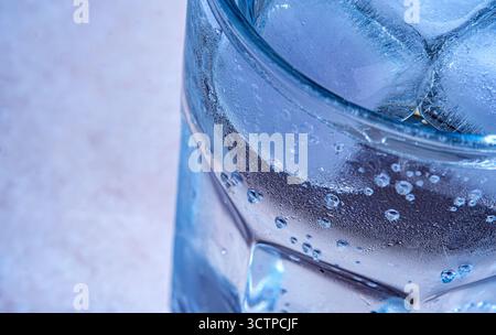 Primo piano di una bevanda fredda ghiacciata con condensa. Un bicchiere freddo pieno di cubetti di ghiaccio e acqua rinfrescante. Mostra la condensa dettagliata Foto Stock