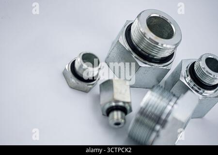 Primo piano di raccordi metallici con superfici filettate su sfondo bianco. Le parti in acciaio lucido evidenziano precisione, durata e design industriale u Foto Stock