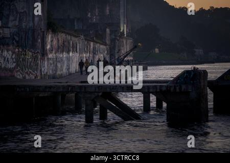 Passeggiata sul lungomare urbano con Street Art e luci della sera - muro dei graffiti sul fiume in un'atmosfera di città Moody Foto Stock