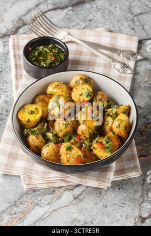 Patate novelle al forno servite con salsa chimichurri appena preparata da vicino in una ciotola sul tavolo. Verticale Foto Stock