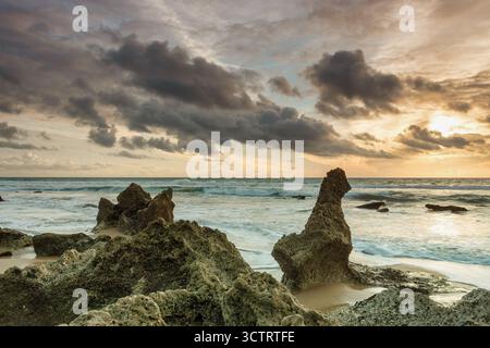 Primo piano delle formazioni rocciose litorali durante il tramonto, che mostrano l'effetto dell'acqua setosa dell'Atlantico e il suggestivo cielo sopra Playa del Puerco Foto Stock