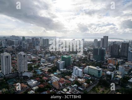 Veduta aerea degli edifici della città che raggiungono il cielo sotto il cielo nuvoloso, Cebu City, Central Visayas, Filippine. Foto Stock