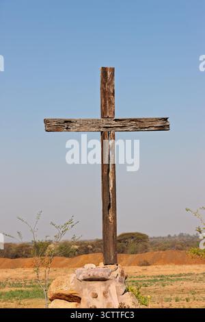 crocifisso a croce in legno d'epoca in cima a pietre rocciose all'aperto nella natura, cielo blu Foto Stock