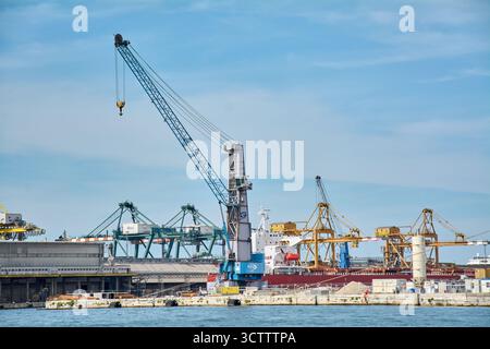 Venezia. Italia - 8 ottobre 2025: Nella zona industriale del Porto di Venezia si vedono diverse gru cargo, tra cui gru mobili e a cavalletto Foto Stock