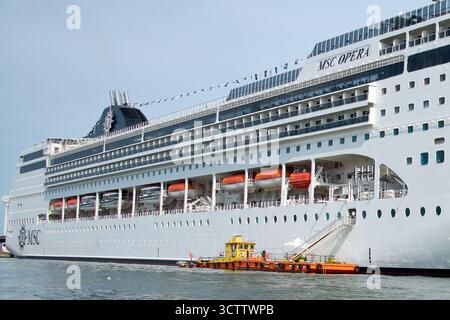 Venezia. Italia - 8 ottobre 2025: Accanto all'MSC Opera è visibile un'imbarcazione di rifornimento o di bunkeraggio, che mostra la logistica di supporto di una nave da crociera. Foto Stock