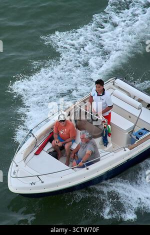 Venezia. Italia - 8 ottobre 2025: Un giovane pilota un motoscafo mentre due uomini più anziani lo accompagnano, rappresentando tre generazioni di una famiglia sulla Ven Foto Stock