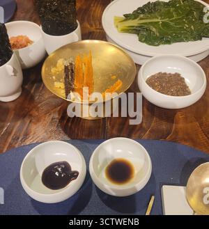 Una fotografia della cucina tradizionale coreana, che include vari piatti come pesce secco o frutta, verdure frondose, salse e alghe marine, serviti su un tavolo di legno a Gyeongju, Corea del Sud. La cucina tradizionale coreana, conosciuta come Hansik (??), è caratterizzata da una varietà di contorni, chiamati banchan (??), serviti insieme a una portata principale di riso, zuppa e spesso stufato. Gyeongju (??) è rinomato per il suo ricco patrimonio culturale e le pratiche culinarie tradizionali. 2025. Foto Stock