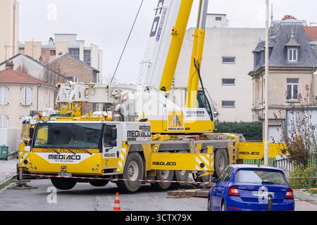 Nancy, Francia - Vista su una gru mobile bianca e gialla Liebherr LTM 1230-5.1 su una strada per sollevare componenti telefonici sul tetto di una torre. Foto Stock