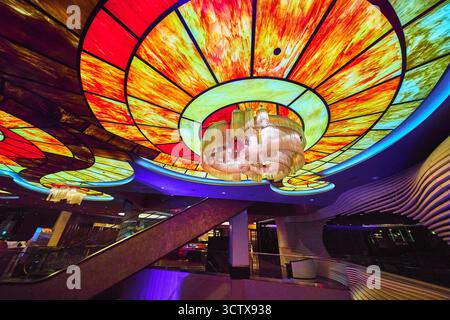Vivace soffitto in vetro colorato con lampadario e scala mobile al casinò di Las Vegas Foto Stock