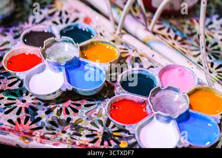 Primo piano di una tavolozza metallizzata a forma di fiore piena di vivaci colori ad acquerello. Forniture artistiche essenziali per progetti di pittura. Foto Stock