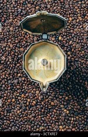 Vecchia macchina per il caffè geyser con bevanda appena preparata sullo sfondo dei chicchi di caffè tostati, primo piano, vista dall'alto, spazio per copiare. Concetti di COF Foto Stock