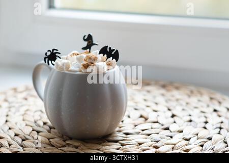 Cioccolata calda di Halloween o caffè con marshmallow e divertenti decorazioni spaventose sul davanzale della stagione. Bevande calde autunnali. Primo piano. Foto Stock