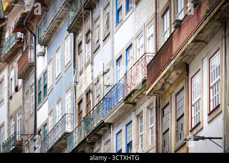 Una veduta stretta delle facciate residenziali di Porto. Evidenzia l'affascinante decadimento dei balconi arrugginiti e delle colorate pareti ricoperte di piastrelle Foto Stock