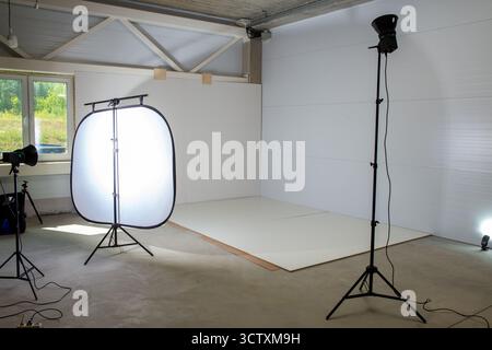 Area fotografica in un angolo della fabbrica per la fotografia dei prodotti, con stroboscopiche da studio e un ampio softbox che crea un'illuminazione soffusa e professionale. Foto Stock