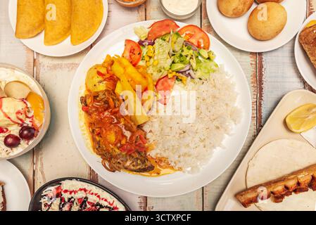 Pesce fritto di Cartagena con patacones verdi, riso al cocco e insalata di avocado, servito su una foglia di banana fresca Foto Stock