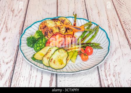 Verdure di stagione alla griglia con asparagi selvatici alla griglia, peperoni arrostiti e melanzane grigliate, servite su un piatto rustico di legno. Foto Stock