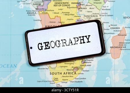 Avvicinati a uno smartphone con la parola geografica sullo schermo con un'immagine consumata sopra la mappa politica dell'africa meridionale Foto Stock