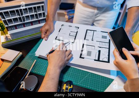 Ingegneri e architetti analizzano i modelli di costruzione e discutono le strategie di progetto, combinando conoscenze tecniche e idee creative per ottenere successo Foto Stock