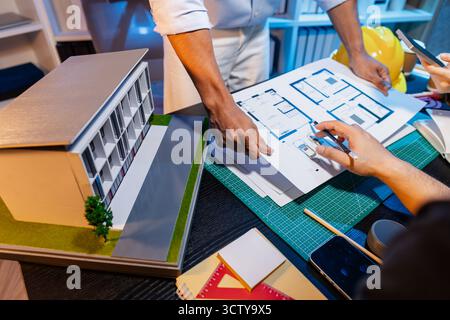 Ingegneri e architetti analizzano i modelli di costruzione e discutono le strategie di progetto, combinando conoscenze tecniche e idee creative per ottenere successo Foto Stock