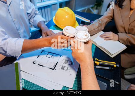 Ingegneri e architetti analizzano i modelli di costruzione e discutono le strategie di progetto, combinando conoscenze tecniche e idee creative per ottenere successo Foto Stock