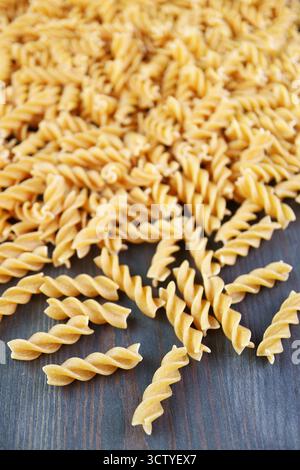 Mucchio di Fusilli di grano intero crudo sparsi su fondo in legno Foto Stock