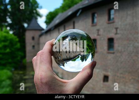 Mano con la sfera dell'obiettivo attraverso la quale è stato fotografato il castello di Paffendorf a Bergheim, Renania settentrionale-Vestfalia, Germania Foto Stock