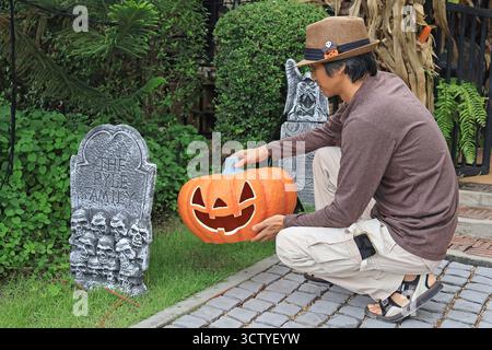 Un uomo che decora il cortile con Jack o'lantern Pumpkins per Halloween Holiday Foto Stock