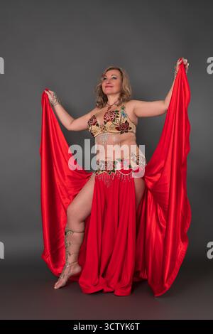 Giocosa donna adulta di mezza età ballerina vestita con costume da ballo - reggiseno, gonna lunga ruvida con fessura e non indossa scarpe, performi Foto Stock