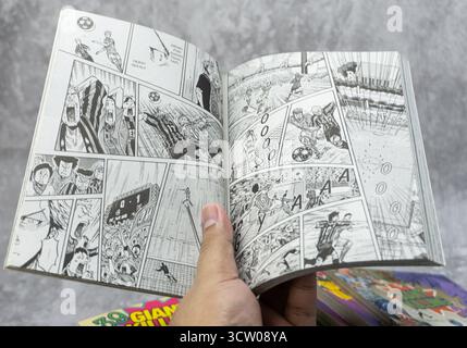 South Kalimantan, Indonesia - 12 08 2023 : Una pila di fumetti o manga giapponesi con il titolo Giant Killing con una pagina aperta su sfondo grigio con Foto Stock