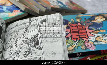 South Kalimantan, Indonesia - 12 08 2023 : Una pila di fumetti o manga giapponesi con il titolo Giant Killing con una pagina aperta su sfondo grigio con Foto Stock