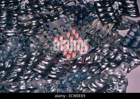 Un mucchio di confezioni di pillole vuote e usate - una confezione di compresse rosa stesa sopra - l'uso eccessivo di pillole può essere pericoloso. Foto Stock