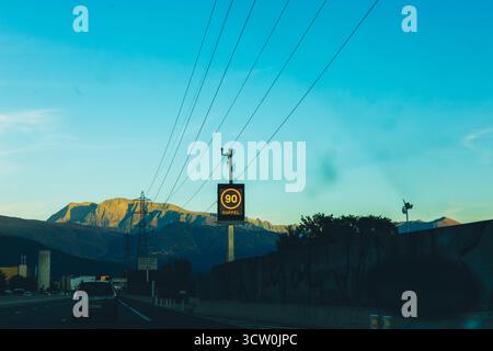 Segnale digitale del limite di velocità che mostra 90 km su un'autostrada francese. Viaggio panoramico con montagne sullo sfondo e cielo azzurro. Foto di alta qualità Foto Stock