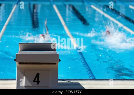 Dettaglio del blocco iniziale con il numero 4. Sullo sfondo i nuotatori stanno nuotando il dorso Foto Stock