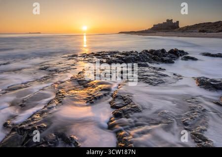 Alba sul castello di Bamburgh e sulla spiaggia, Northumberland, Inghilterra. Inverno (marzo) 2025. Foto Stock