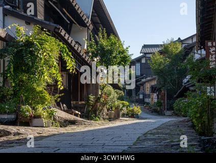 Magome, Giappone - 19 luglio 2025: Fiori e cartelli lungo il sentiero acciottolato che attraversa Magome Foto Stock