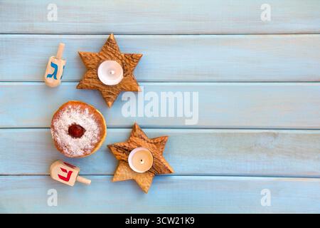 Candelabri in legno a forma di stella, ciambella e ciambelle sullo sfondo di tavole di legno dipinte di blu con spazio per il testo. Festa ebraica Hanukkah. Foto Stock