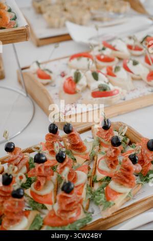 Primo piano di un tavolo a buffet con tartine antipasti con salame formaggio e olive. Una selezione di mini-panini freschi e canape di olive su spiedini Foto Stock