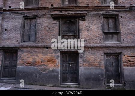 Edificio a tre piani in mattoni rossi con porte e finestre in legno antico che mostrano un fascino rustico e storico e segni di usura. Foto Stock