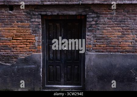 Edificio a tre piani in mattoni rossi con porte e finestre in legno antico che mostrano un fascino rustico e storico e segni di usura. Foto Stock