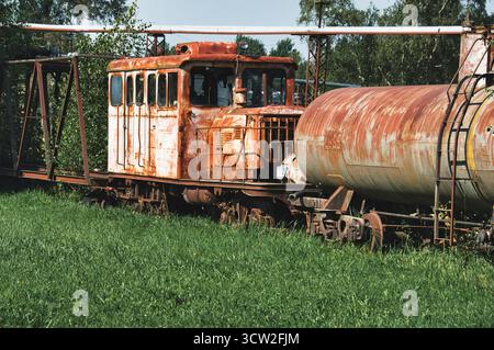 Ruggine abbandonata per il motore di treni industriali e autocisterne nel campo d'erba Foto Stock