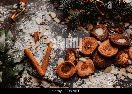 Un ambiente rustico per le vacanze con un barattolo di biscotti fatti in casa, circondato da bastoncini di cannella e luci festive. I rami di pino aggiungono un'atmosfera accogliente e calda Foto Stock