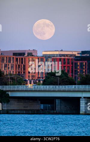 Harvest Moon Over 14th Street Bridge Southwest Waterfront Washington DC // WASHINGTON DC - il 2025 ottobre Harvest Moon si erge sopra il 14th Street Bridge e lo skyline del Southwest Waterfront il 6 ottobre 2025. Questa luna piena, che si trova più vicino all'equinozio autunnale, illumina il fiume Potomac. Il complesso 14th Street Bridge collega Washington D.C. con Arlington, Virginia, trasportando le principali strade e linee ferroviarie. Il Southwest Waterfront è un vivace quartiere noto per il suo sviluppo moderno e le attrazioni culturali lungo il canale di Washington. Questa vista cattura la lan urbana Foto Stock