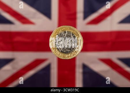 Moneta da una sterlina britannica con Union Jack Flag sullo sfondo Foto Stock