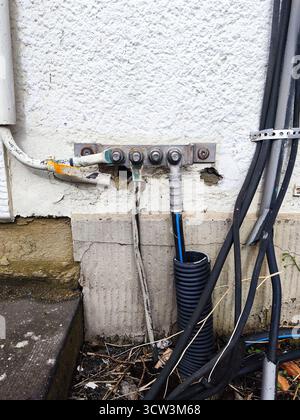 Terminale di collegamento a massa elettrica esterno su una parete in stucco bianco ruvido Foto Stock