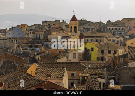 Il centro storico della città di Corfù (Kerkyra) mostra le sue case color pastello e la torre rossa della chiesa illuminata dalla calda luce serale. Foto Stock
