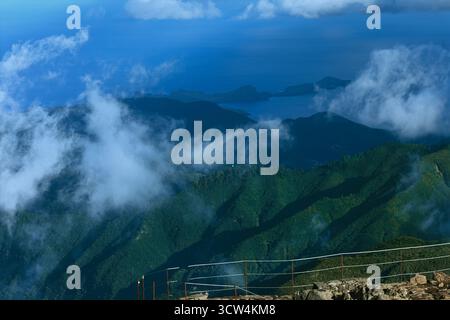 L'aspro crinale di montagna avvolto dalla nebbia si affaccia su ripidi pendii verdi e sul lontano orizzonte Atlantico, le nuvole attraversano profonde vallate sotto il cielo blu Foto Stock