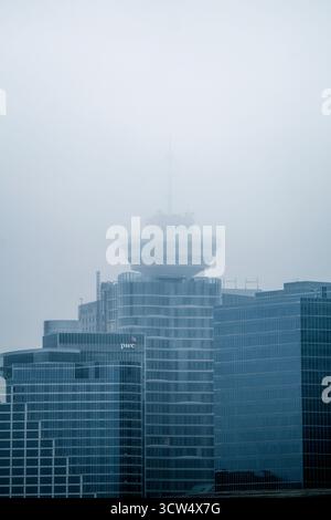 La fitta nebbia copre lo skyline di Vancouver, avvolgendo i moderni grattacieli. Solo la sommità di una torre è visibile, creando un'atmosfera misteriosa nel c Foto Stock