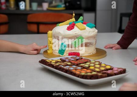 Primo piano della torta di compleanno per bambini e biscotti al cioccolato con le mani dei bambini Foto Stock